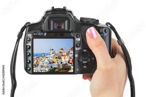 Foto: Camera in hand and Santorini (Greece) view Camera in hand and Santorini (Greece) view