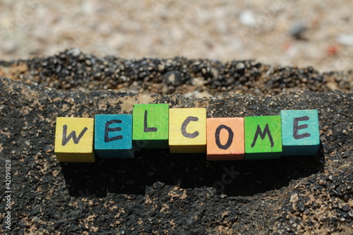 Photo: The word Welcome - written on wood cubes, at the beach The word Welcome - written on wood cubes, at the beach