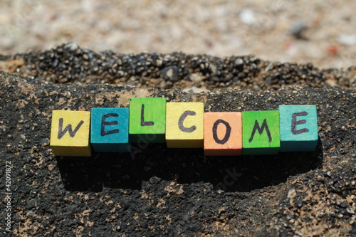 Photo: The word Welcome - written on wood cubes, at the beach The word Welcome - written on wood cubes, at the beach