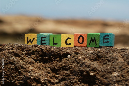 Photo: The word Welcome - written on wood cubes, at the beach The word Welcome - written on wood cubes, at the beach