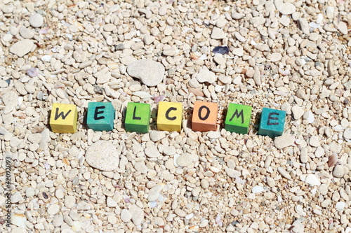 Photo: The word Welcome - written on wood cubes, at the beach The word Welcome - written on wood cubes, at the beach