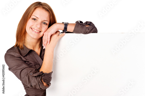 Photo: Happy Businesswoman standing and holding a white empty billboard Happy Businesswoman standing and holding a white empty billboard