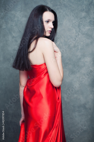 Photo: Beautiful caucasian lady with long dark hair in red sateen Beautiful caucasian lady with long dark hair in red sateen