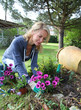 Cheerful blond woman planting flowers in garden