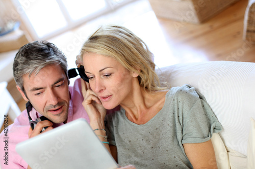Photo: Couple listening to music at home with tablet Couple listening to music at home with tablet