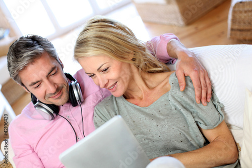 Photo: Couple listening to music at home with tablet Couple listening to music at home with tablet