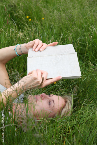 Foto: View of woman reading book in green garden View of woman reading book in green garden