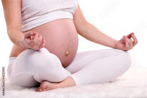 Photo: Young pregnant woman sitting in a lotus position Young pregnant woman sitting in a lotus position