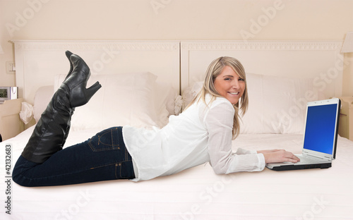 Foto: Woman using laptop in bed Woman using laptop in bed