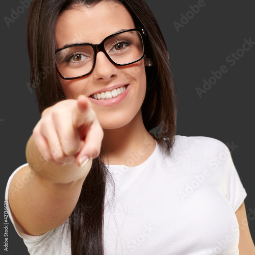 Photo: portrait of young woman pointing with finger against a black bac portrait of young woman pointing with finger against a black bac
