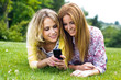 dos jóvenes amigas en el parque con un teléfono móvil