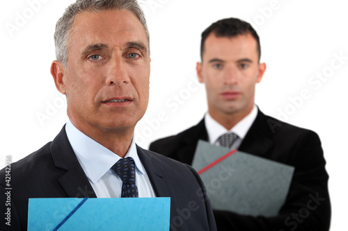 Photo: businessman with his assistant trailing behind him businessman with his assistant trailing behind him