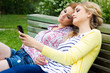 dos jóvenes amigas en el parque con un teléfono móvil
