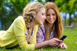 dos jóvenes amigas en el parque con un teléfono móvil