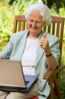 ältere Frau im Garten mit Laptop