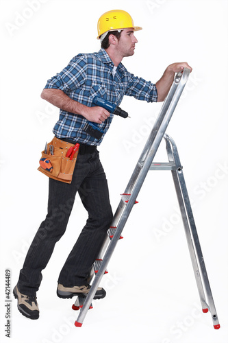 Photo: A handyman climbing a ladder. A handyman climbing a ladder.