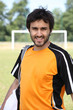 Male footballer stood in front of pitch