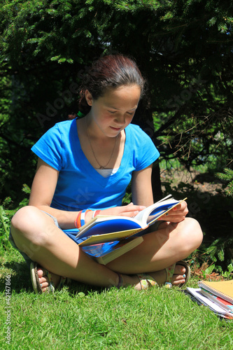 Photo: Young girl doing homework outdoors Young girl doing homework outdoors