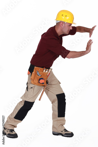 Photo: Tradesman pushing an invisible wall Tradesman pushing an invisible wall
