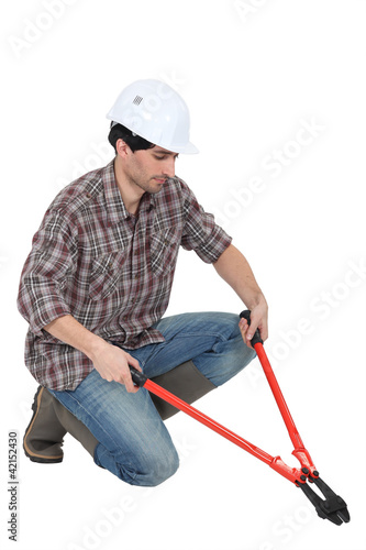 Foto: Man kneeling with bolt-cutters Man kneeling with bolt-cutters