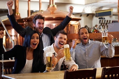 Photo: Happy fans watching TV in pub cheering Happy fans watching TV in pub cheering