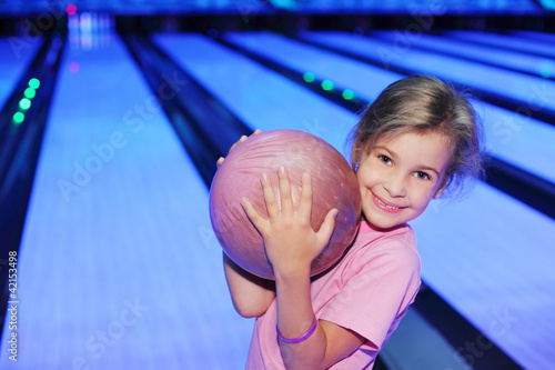 Foto: Smiling little girl holds ball in bowling club Smiling little girl holds ball in bowling club