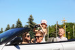 Beautiful father, mother and children ride in convertible car