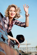 Blonde woman in car making goodbye wave
