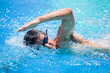Young man swimming the front crawl in a pool
