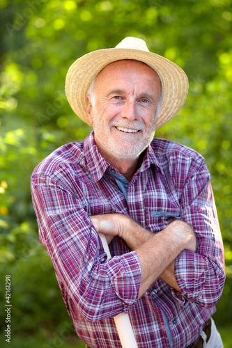 Photo: Senior gardener with straw hat Senior gardener with straw hat
