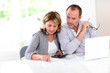 Couple reading construction plan at home with use of laptop