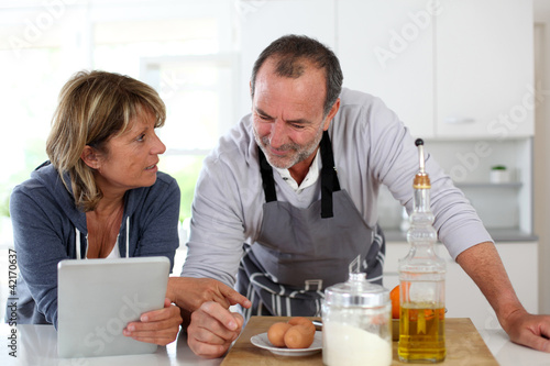 Photo: Senior couple having fun in home kitchen Senior couple having fun in home kitchen