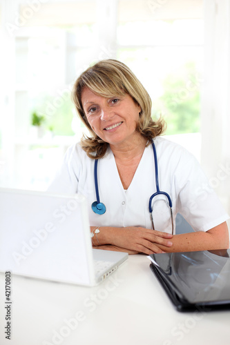 Photo: Portrait of mature nurse sitting at her desk Portrait of mature nurse sitting at her desk