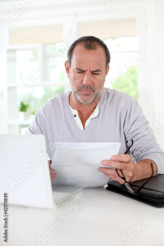 Foto: Senior man being puzzled with tax documents Senior man being puzzled with tax documents
