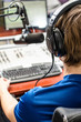 Photo: Dj working in front of a microphone on the radio, from the back Dj working in front of a microphone on the radio, from the back