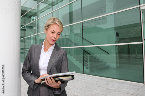 Photo: Mature businesswoman standing in front of modern building Mature businesswoman standing in front of modern building