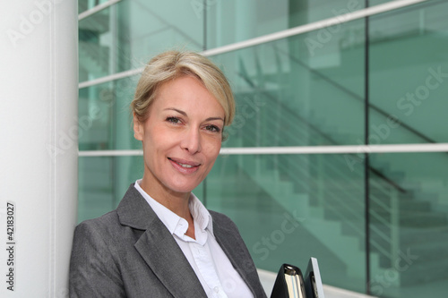 Foto: Mature businesswoman standing in front of modern building Mature businesswoman standing in front of modern building