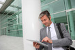 Businessman standing outside building with electronic tablet