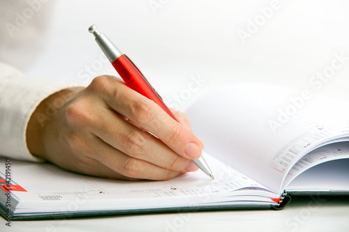 Foto: Closeup view of a businesswoman writing in a datebook Closeup view of a businesswoman writing in a datebook