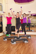 drei junge Frauen am Aerobic Stepper im Gymnastikraum