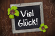 Tafel auf Holzwand mit Kleeblättern und Viel Glück