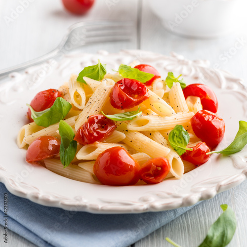 Photo: Penne pasta with cherry tomatoes and basil on a plate Penne pasta with cherry tomatoes and basil on a plate