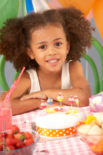 Photo: Young girl with birthday cake at party Young girl with birthday cake at party