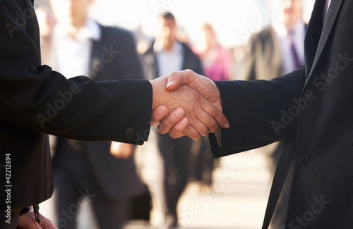 Photo: Businessman and business woman shaking hands in street Businessman and business woman shaking hands in street