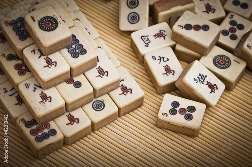 Photo: Old chinese game mahjongg on bamboo mat background Old chinese game mahjongg on bamboo mat background