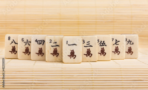 Photo: Old chinese game mahjongg on bamboo mat background Old chinese game mahjongg on bamboo mat background