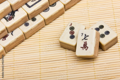 Photo: Old chinese game mahjongg on bamboo mat background Old chinese game mahjongg on bamboo mat background