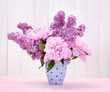 spring flowers in cup on table on white wooden background