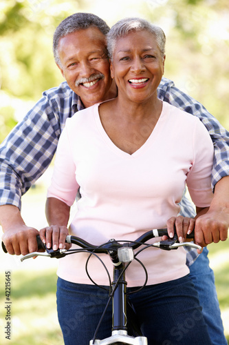 Photo: Senior couple cycling in park Senior couple cycling in park