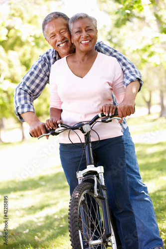 Photo: Senior couple cycling in park Senior couple cycling in park